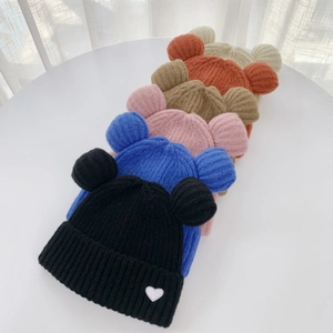 Close-up of knit beanies with bear ears and heart patch in diverse color palette