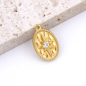 Macro detail of gold oval starburst pendant with crystal and hammered metal texture