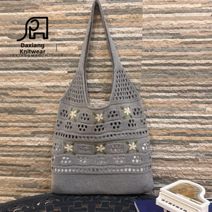 Detail of grey handmade crochet tote bag with flower embroidery on a stone wall