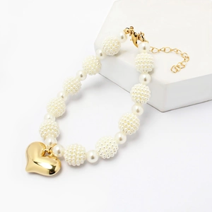 Elegant pearl pet necklace with a polished gold heart pendant on a white pedestal