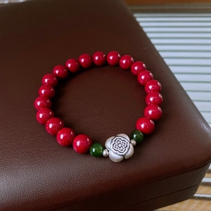 Macro detail of cinnabar beads and silver flower pendant on a jade stone bracelet