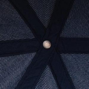 Detail of the navy denim baseball cap interior featuring reinforced cross seams and metal rivet