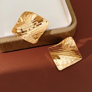 Détail des boucles d'oreilles carrées plaquées or 18 carats avec texture martelée élégante