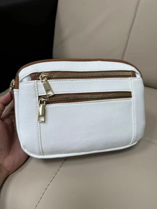 Close-up of white lychee texture PU crossbody bag with dual golden zippers and brown trim