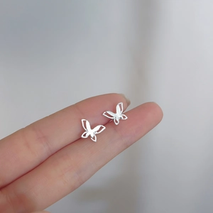 Close-up of 925 sterling silver butterfly stud earrings held on a finger for size
