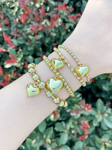 Detail of four-piece set 18k gold plated beaded bracelets with heart pendants on wrist