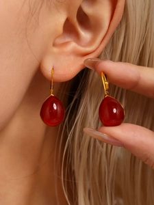 Detailed close-up of woman wearing elegant deep red resin waterdrop earrings with gold hooks