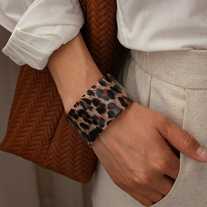 Detailed view of leopard print acrylic wide bangle on wrist with stylish outfit