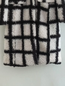 Close-up of black and white plaid pattern on high-quality plush lamb wool coat fabric