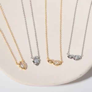 Detailed shot of four gold and silver necklaces with marquise and teardrop zircon pendants