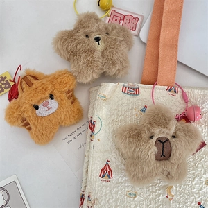 Close-up of star-shaped plush bear and cat charms with fine embroidery and bells