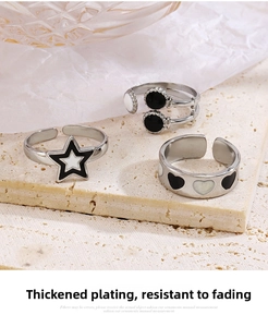 Macro detail of adjustable stainless steel rings with black enamel star and heart patterns