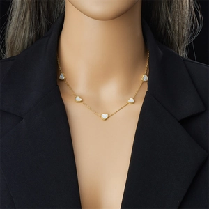 Golden heart necklace set with white shell inlay pendant worn on female model