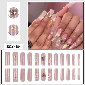 Pink press-on nails with white flowers, gold butterflies and crystal heart charms
