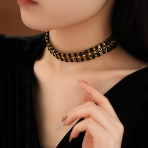 Close-up of black beaded choker with gold metal accents on model's neck
