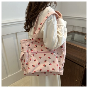 Pink corduroy tote bag with strawberry pattern shown from a side view on a model