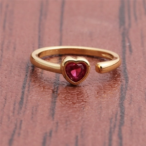Macro shot of gold-plated open ring with ruby heart stone on a wooden surface