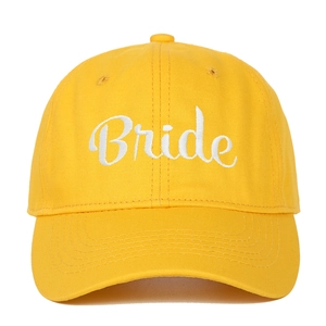 Close-up of white cursive Bride embroidery on a vibrant yellow cotton baseball cap