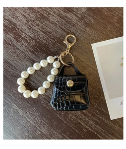Detail view of mini black faux crocodile leather bag charm with white pearl handle