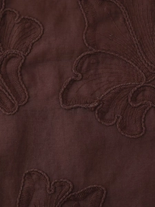 Vue macro de broderie papillon détaillée sur un tissu textile marron foncé de qualité
