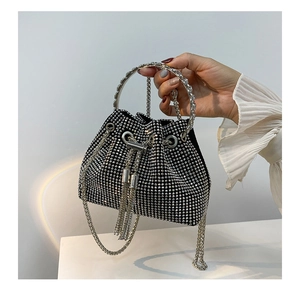 Detail of black rhinestone bucket bag with silver metal ring handle and fringe accents