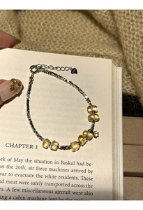 Macro shot of S925 silver beaded bracelet with yellow citrine crystals on a book