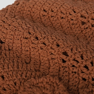 Detailed close-up of brown handmade crochet knit pattern with intricate hollow out texture