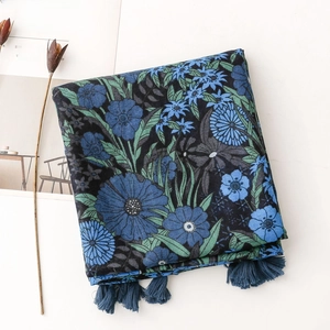 Detailed view of dark blue floral printed scarf with elegant tassel trim and cotton-linen texture