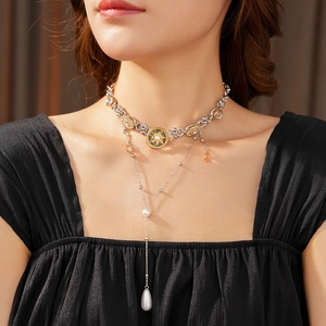 Detail of vintage layered necklace with sun pendant and teardrop pearl on female model
