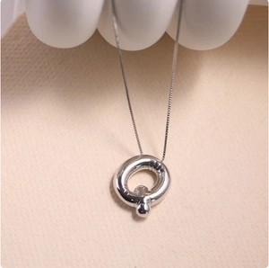 Close-up of a silver polished hollow pendant with a delicate box chain necklace