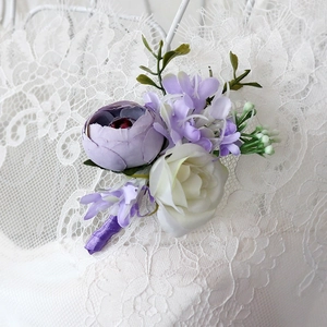 Elegant purple and white silk boutonniere with greenery on white lace for weddings