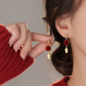 Macro view of red velvet circular disk earrings with golden multi-layered metal pendants