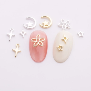 Macro shot of gold and silver cross star alloy nail charms on light pink manicured nails