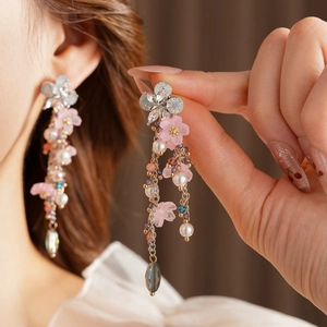 Dettaglio di orecchini vintage a fiore con perle e gocce di cristallo dorato