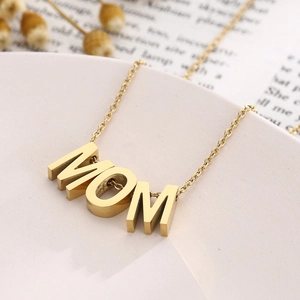Vue détaillée d'un collier avec pendentif lettre MOM dorée sur un plat en céramique