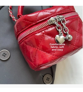 Close-up of red mini quilted crossbody bag with silver heart pendant and chain strap