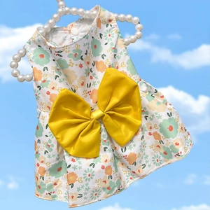 Detail of floral pet dress with a large yellow bow hanging on a pearl hanger