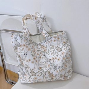 Detailed close-up of rabbit print canvas tote bag with simple wish label on white chair