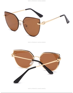 Detail of gold metal cat-eye sunglasses with horse-bit hinge and brown tinted lenses