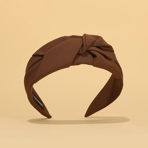 Detailed shot of brown pleated headband showing the handmade label and knotted design