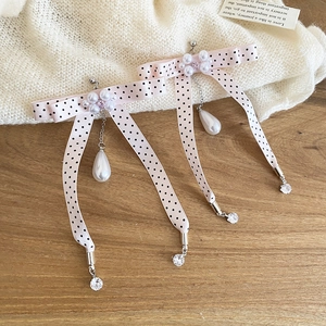 Detail of pink polka dot bow earrings with pearls and crystals on a wooden surface