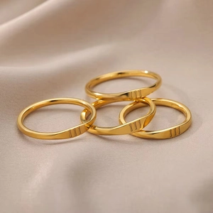 Set of four gold-plated stainless steel angel number 111 rings stacked on beige fabric