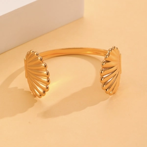 Detalle de un brazalete dorado con forma de concha y texturas acanaladas