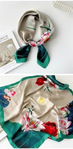 Detail of a square satin scarf with lotus patterns and dark green borders on white desk