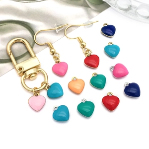 Colorful enamel heart pendants and gold hooks for DIY jewelry making on silk background