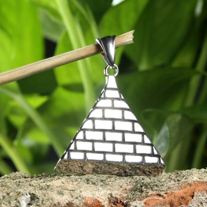 Macro detail of silver pyramid pendant with Eye of Horus textures on wood branch