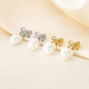 Macro view of crystal bow earrings with large pearl drop on silk fabric