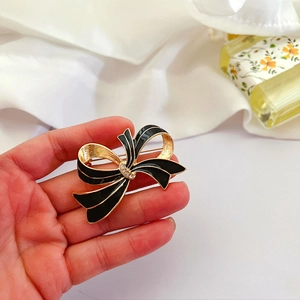 Close-up of vintage black enamel bow brooch with sparkling crystals in gold finish