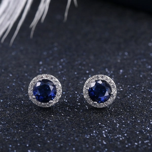 Macro shot of round halo stud earrings with deep blue zircon and white accents