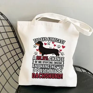 White canvas tote bag with cartoon dachshund print placed on a black metal chair